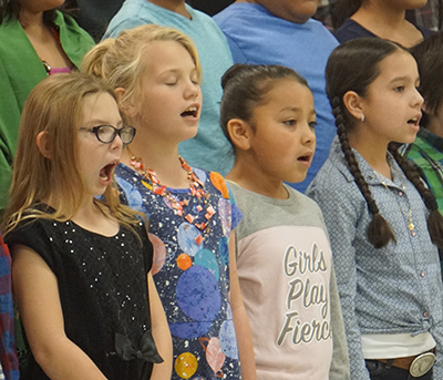 four students with mouth open singing