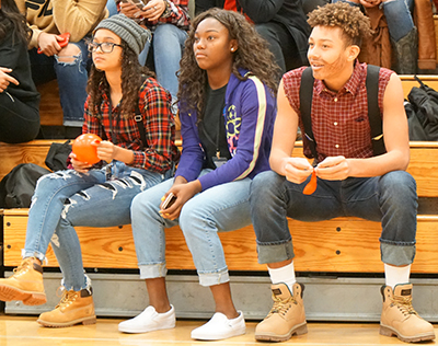 three students sitting in bleachers dressed in plaid