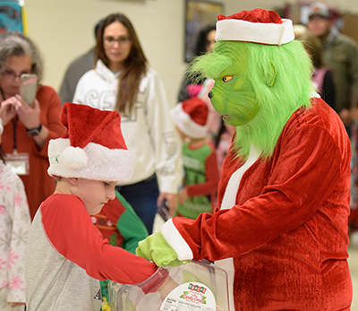 kid in santa hat getting candy from grinch