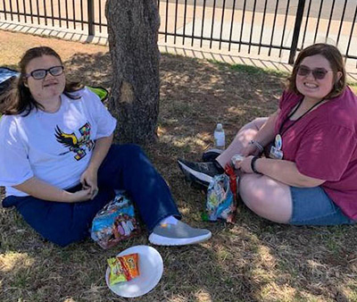 two smiling girls sitting on picnic blanket