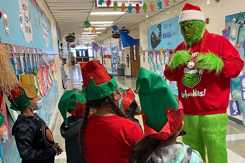 guy in grinch costume talking to students