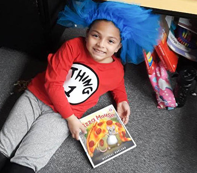 kid on floor in blue wig with book