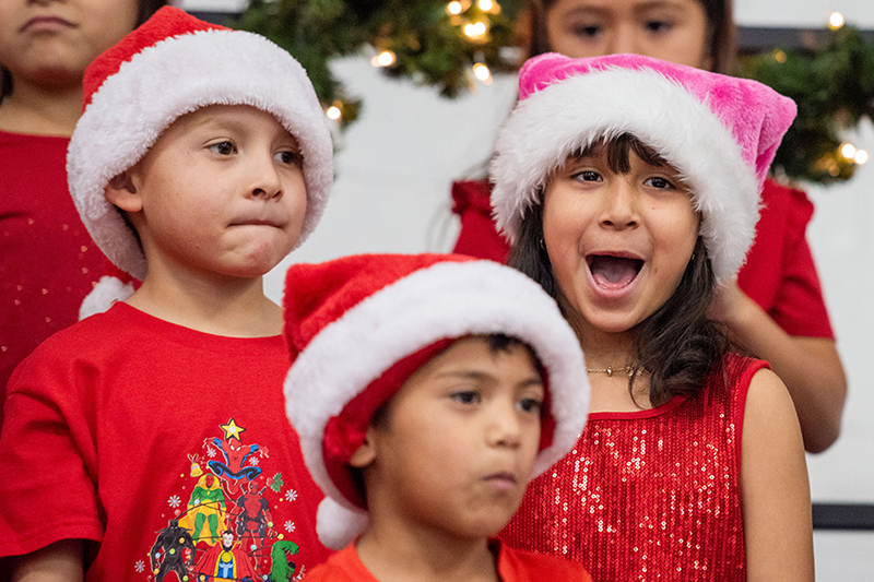 two children in santa hats singing